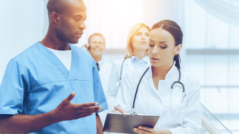 Medical Assistant With Doctor Discussing Patient Notes